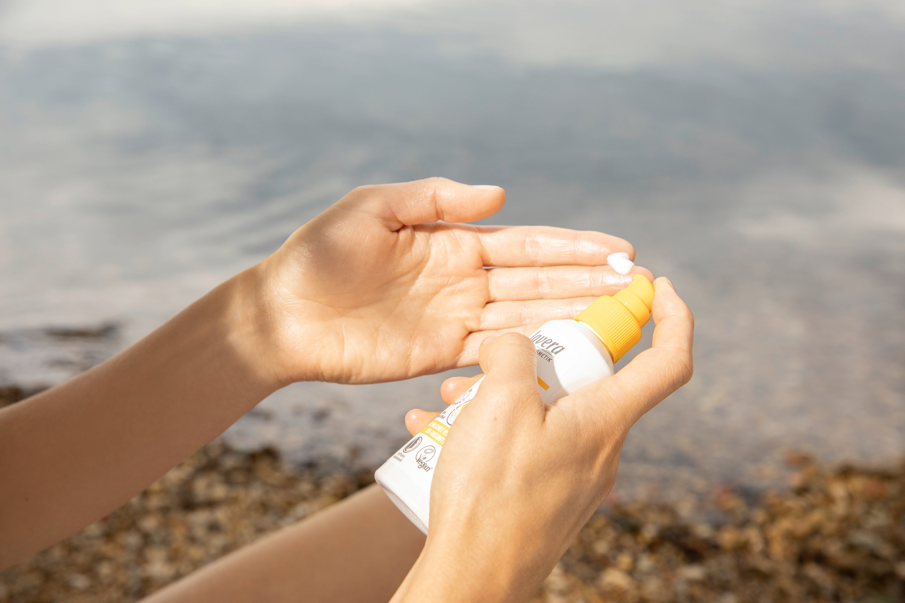 Mani dosano crema solare lavera Sensitiv SPF 30 in spiaggia