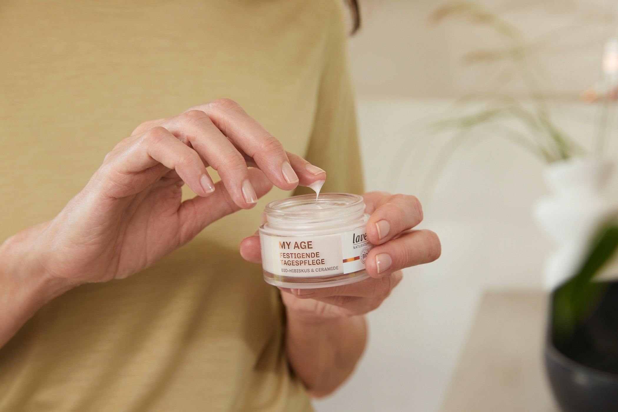 Donna tiene vasetto My Age con una mano e preleva crema con l'altra