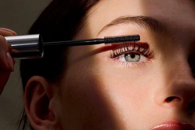 Donna applica mascara sulle ciglia superiori, primo piano dell'occhio