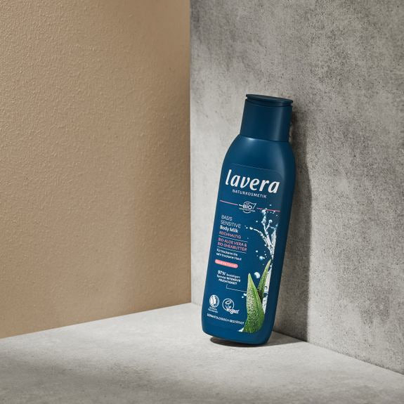 lavera basis sensitive Body Milk in bottiglia blu su piedistallo di pietra