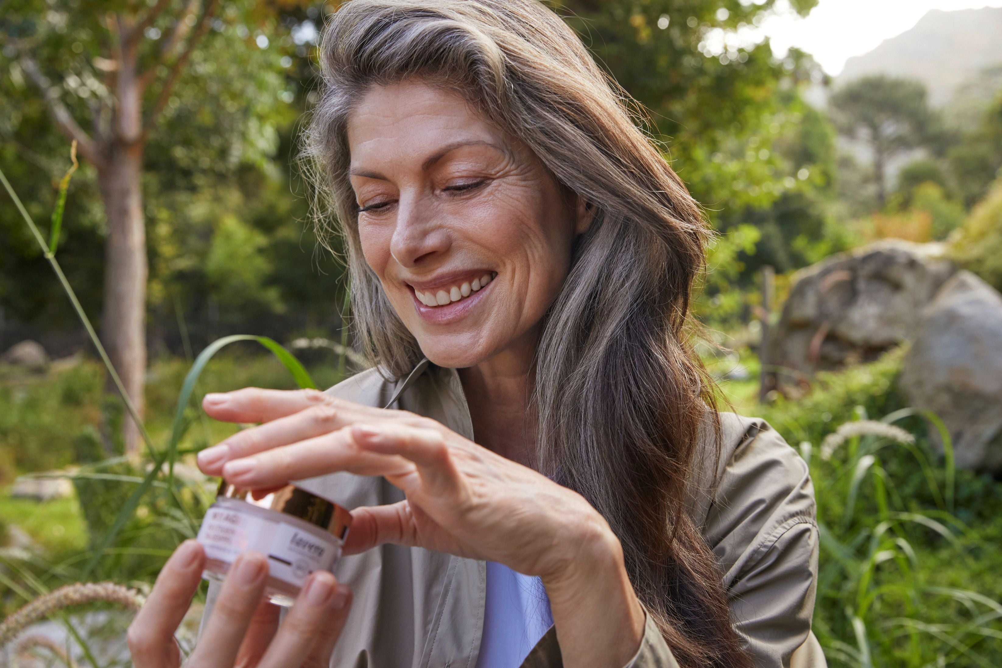 Donna nella natura tiene in mano la crema lavera MY AGE