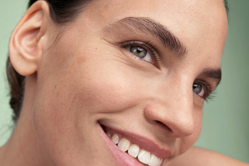 Primo piano di una donna sorridente con pelle pura su sfondo verde