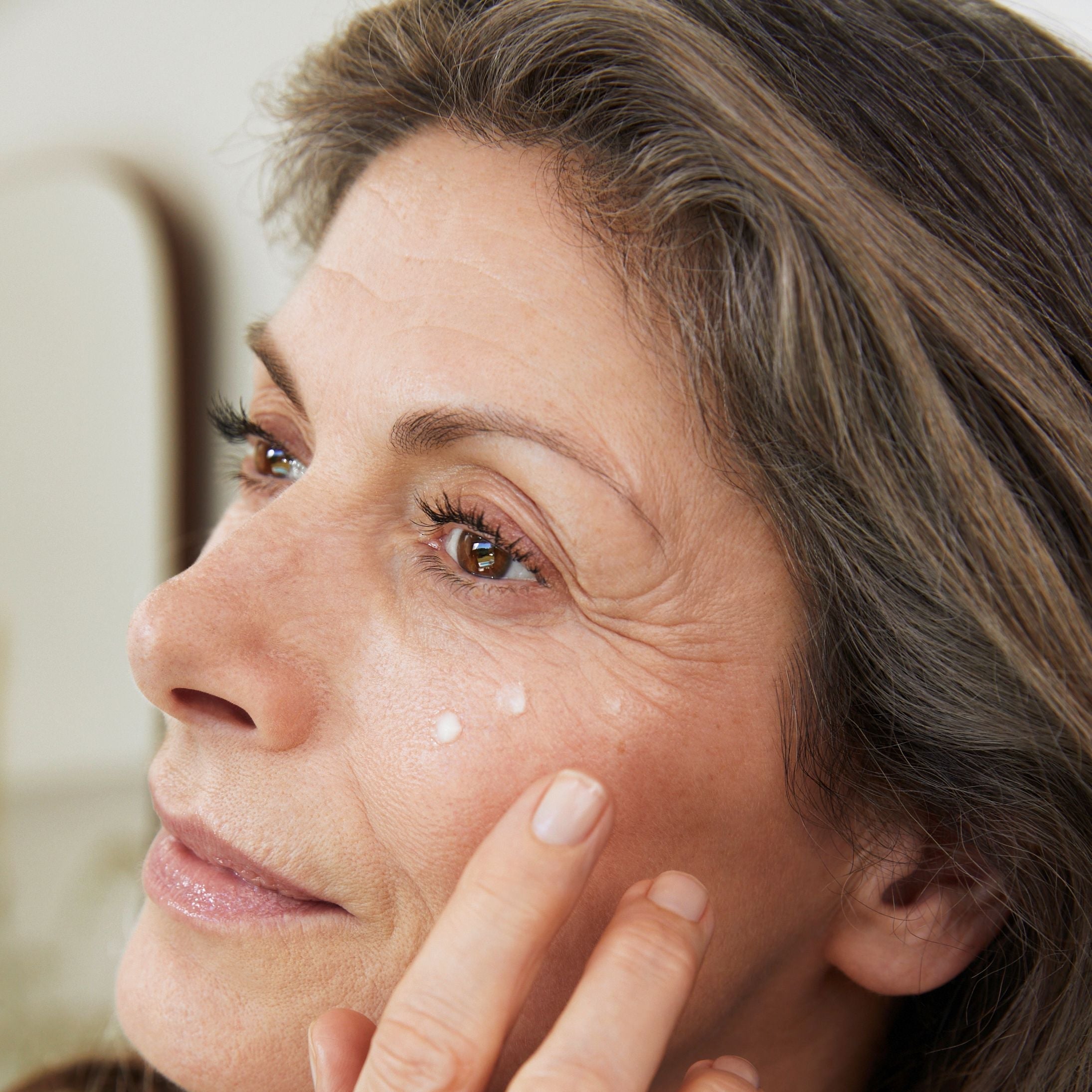 Donna applica crema sotto l'occhio