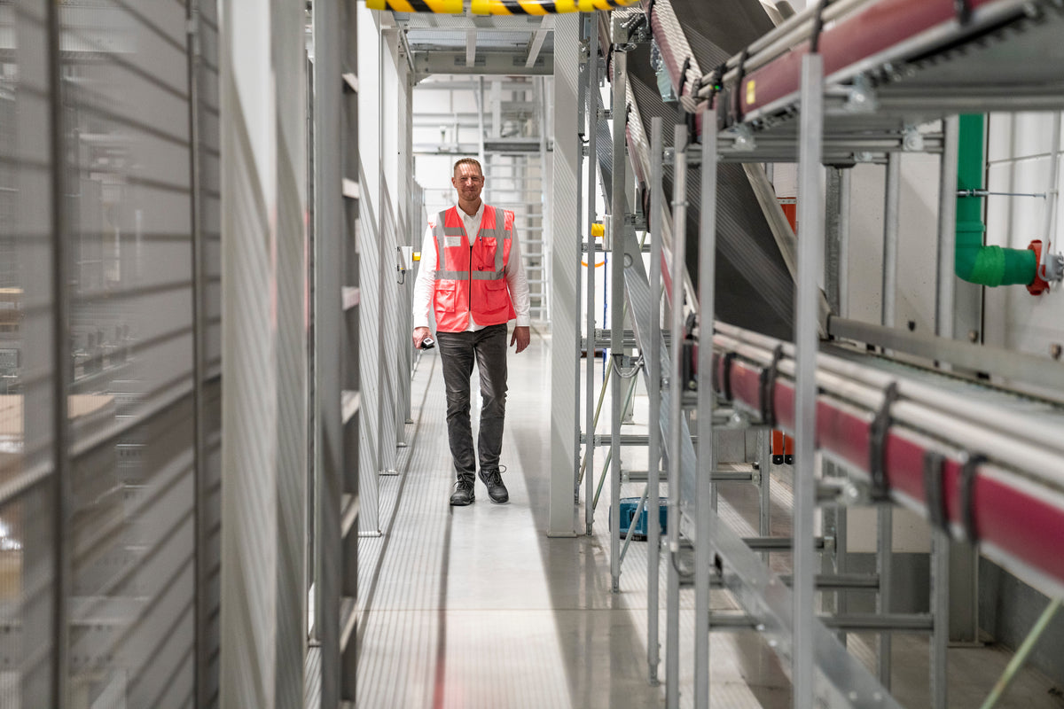 Mann mit roter Weste geht durch einen Korridor im lavera Logistikzentrum