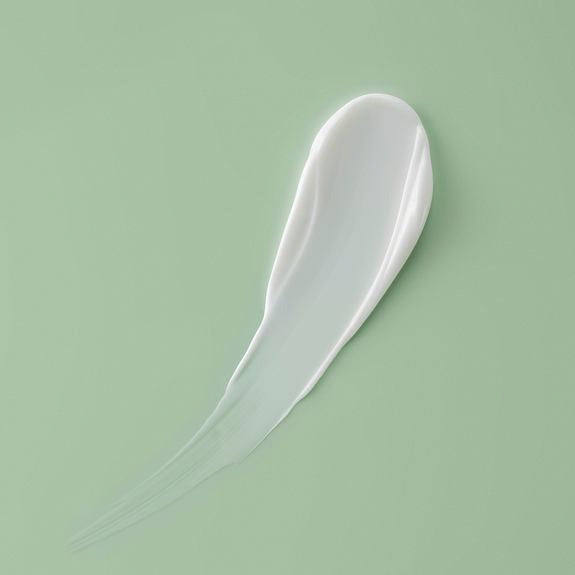 Tratto di crema bianca su superficie verde salvia