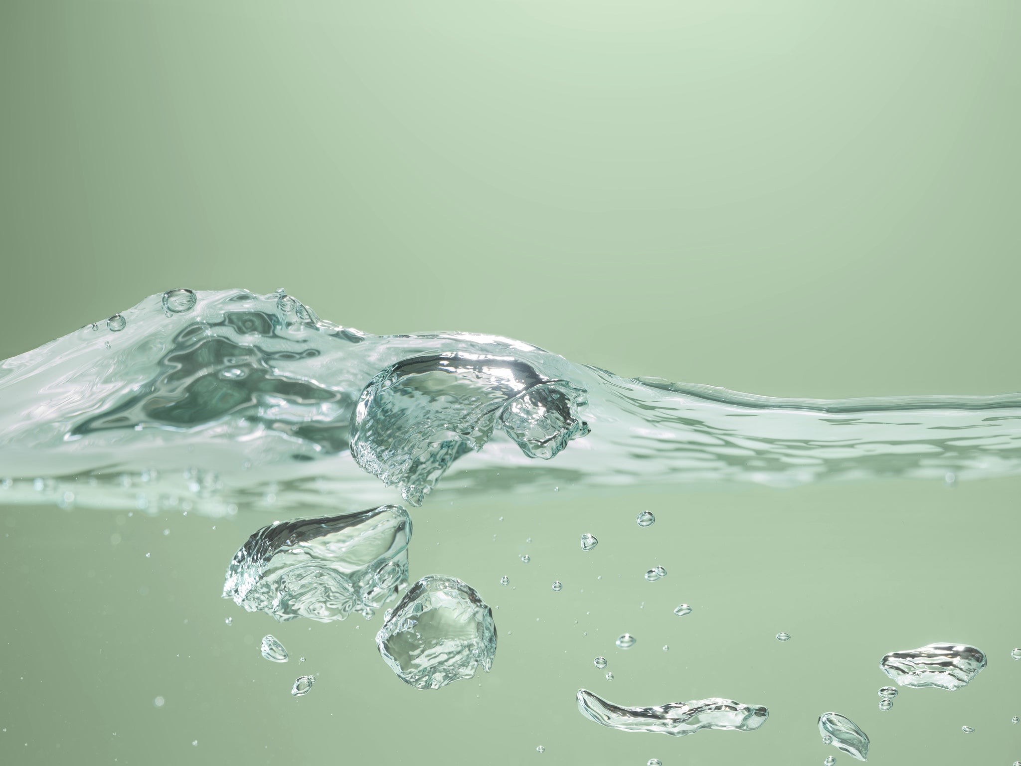 Nahaufnahme einer spritzenden Wasserwelle auf grünem Hintergrund.