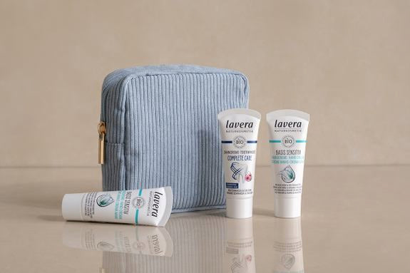 Trousse de toilette bleue avec trois formats voyage lavera sur fond beige
