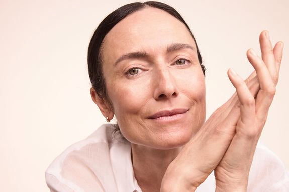 Donna matura con capelli raccolti su sfondo beige caldo