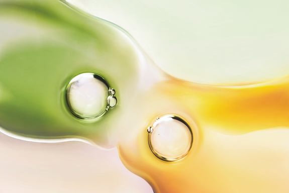 Eine gelbe und eine grüne Flüssigkeit mit je einer Blase laufen ineinander.