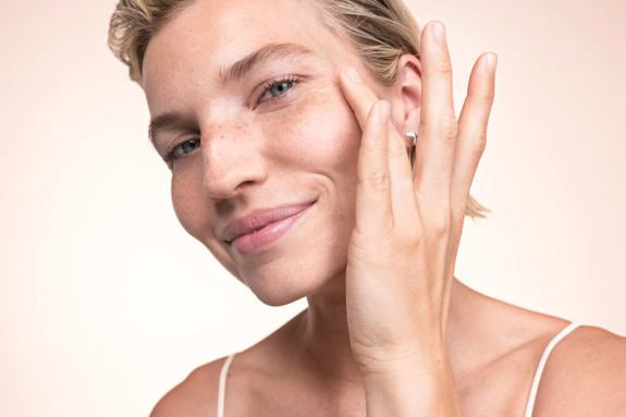 Una donna bionda passa un dito sulla guancia e sorride