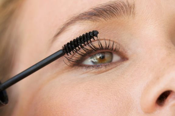 Primo piano di un occhio durante l'applicazione di mascara con lo scovolino