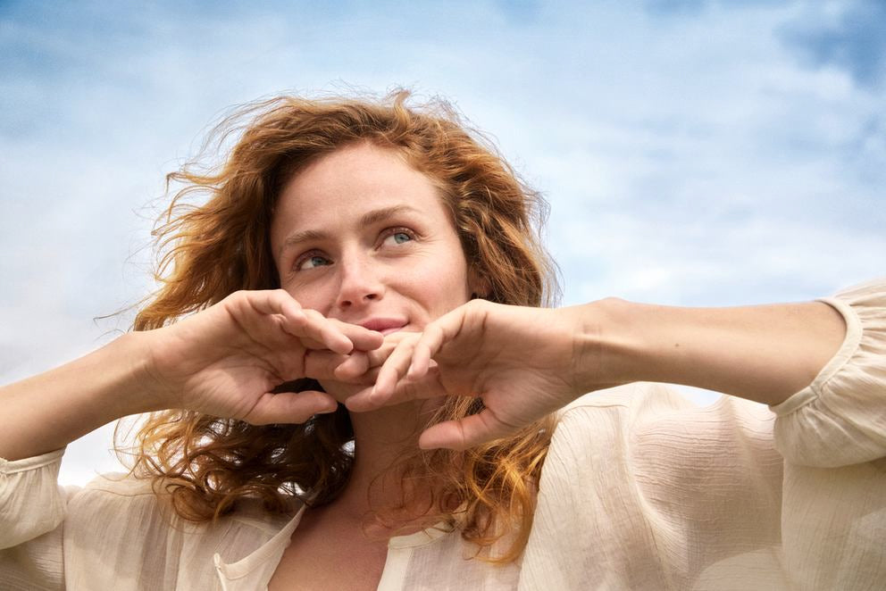 Donna con capelli rossi ricci guarda sorridendo il cielo