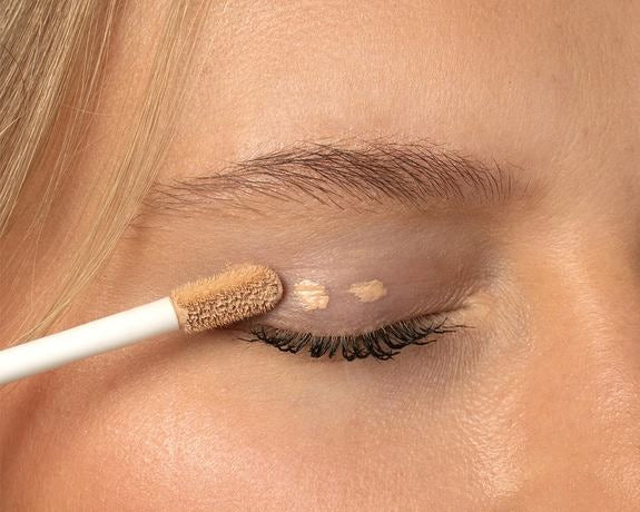 Gros plan d'une paupière avec application de correcteur comme base pour fard à paupières