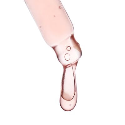 Gros plan de pipette avec liquide rose clair et goutte sur fond blanc